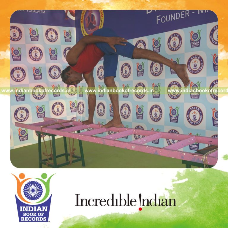 individual holding daksina ardha chandrasana yoga pose on a ladder for record in Indian Book of Records
