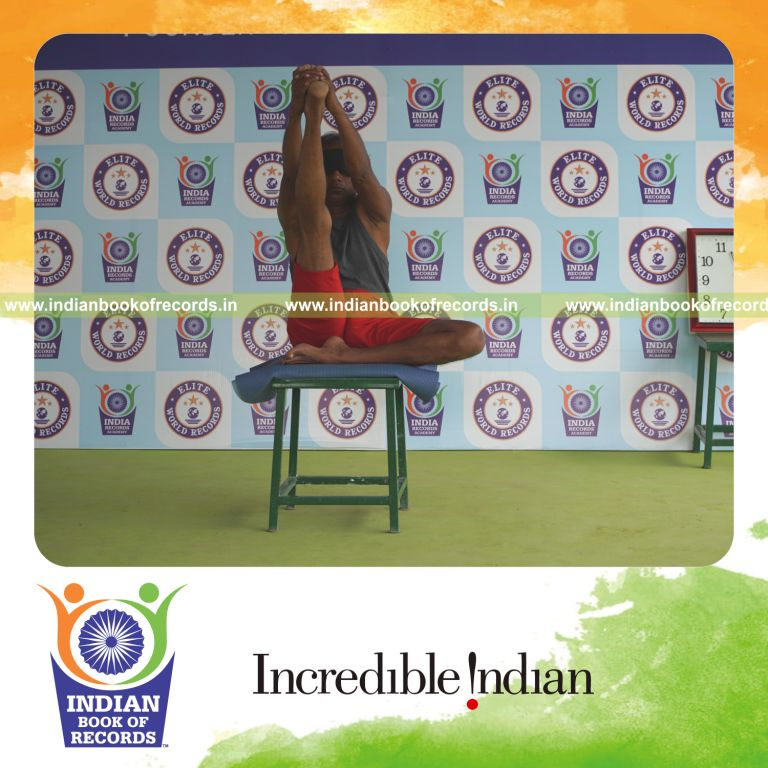 individual holding daksina ardha krounchasana yoga pose blindfolded on a stool for record in Indian Book of Records