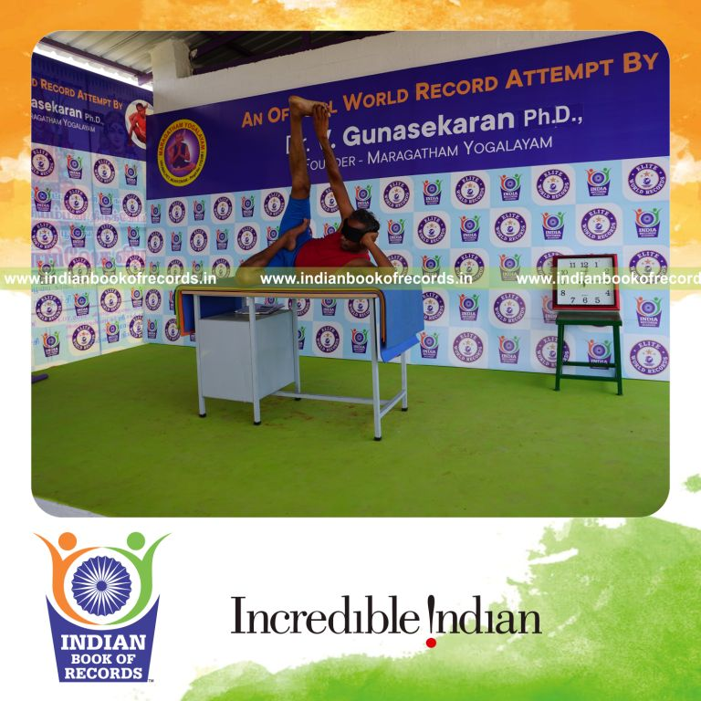 individual holding daksina ardha padma anantasana yoga pose blindfolded on a table for record in Indian Book of Records