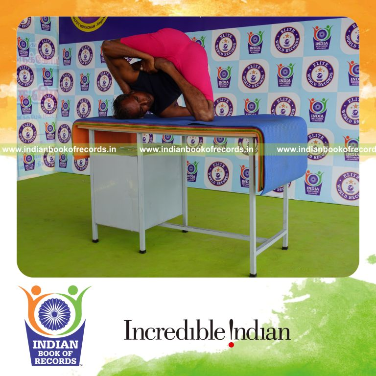 individual holding daksina ardha padma astavakrasana yoga pose on a table for record in Indian Book of Records