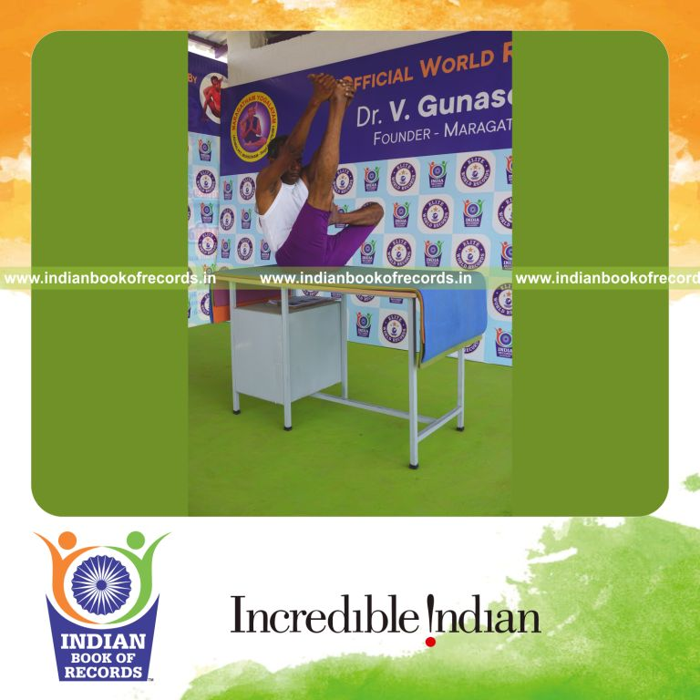 individual holding daksina ardha padma krounchasana yoga pose on a table for record in Indian Book of Records