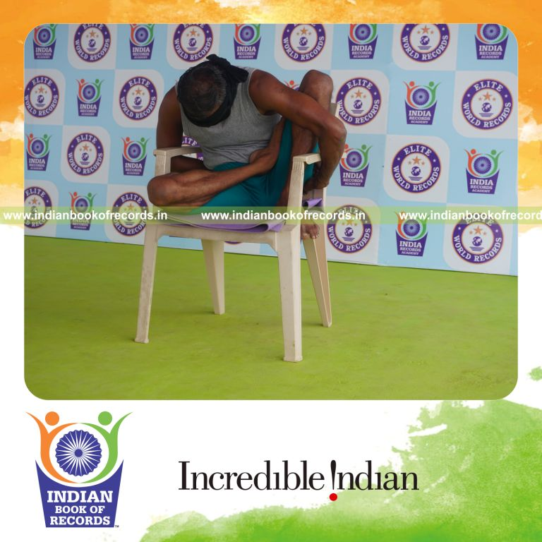 individual holding daksina ardha padma marichyasana yoga pose blindfolded on a chair for record in Indian Book of Records