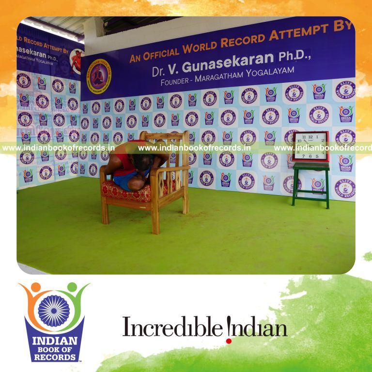 individual holding daksina ardha padma marichyasana yoga pose on a chair for record in Indian Book of Records