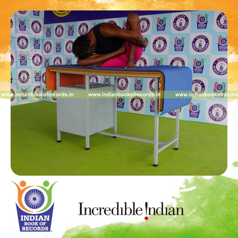 individual holding daksina ardha padma marichyasana yoga pose on a table for record in Indian Book of Records