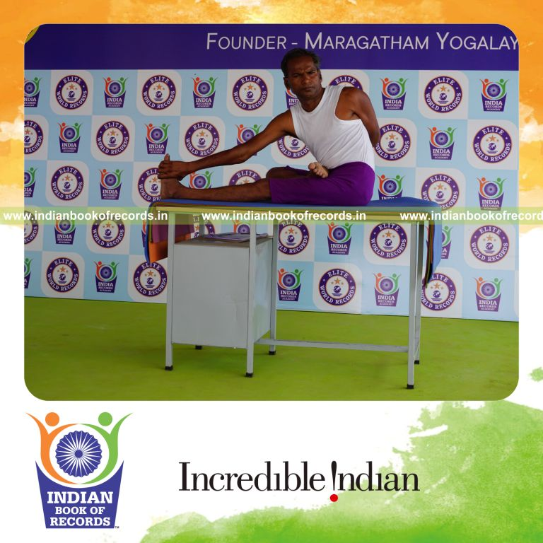 individual holding daksina ardha padma matsyendrasana yoga pose on a table for record in Indian Book of Records