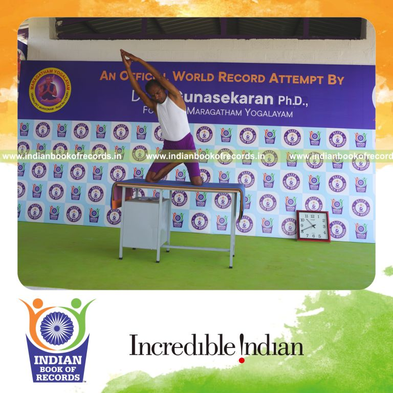 individual holding daksina ardha padma ustraa konasana yoga pose on a table for record in Indian Book of Records