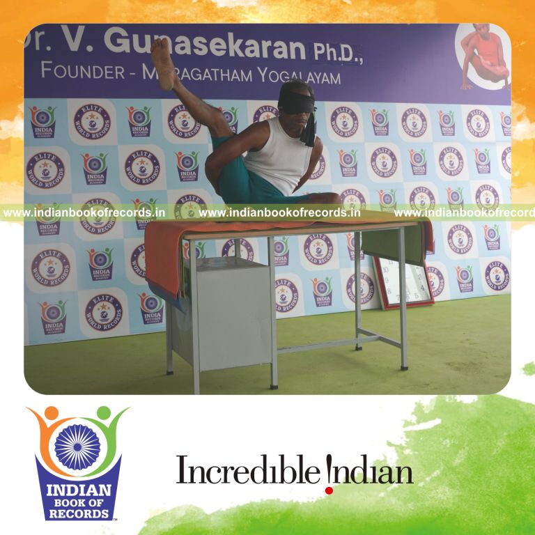 individual holding daksina ardha parsva krounchasana yoga pose blindfolded on a table for record in Indian Book of Records
