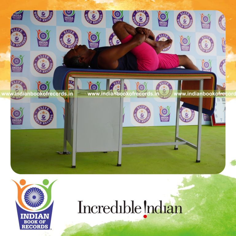 individual holding daksina ardha pavanamuktasana yoga pose on a table for record in Indian Book of Records