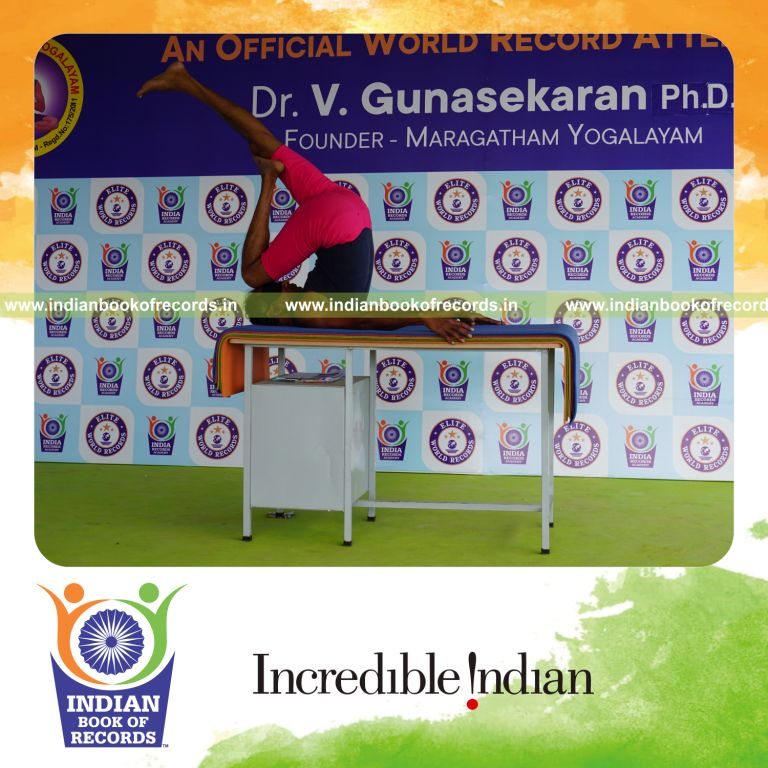 individual holding daksina ardha salamba sarvangasana yoga pose blindfolded on a table for record in Indian Book of Records