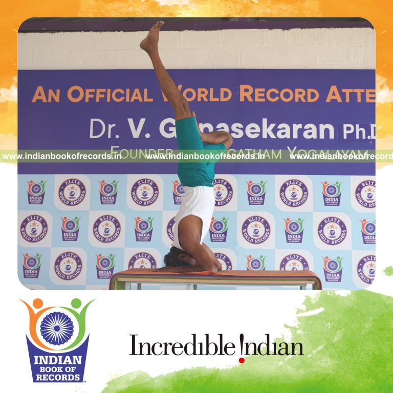 an individual holding daksina ardha salamba sirsasana yoga pose blindfolded on a table continuously for the longest duration with balance and control for a record in Indian Book of Records