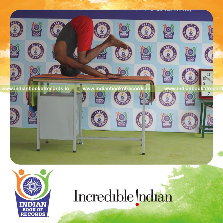 individual holding daksina ardha sarvangasana yoga pose blindfolded on a table for record in Indian Book of Records