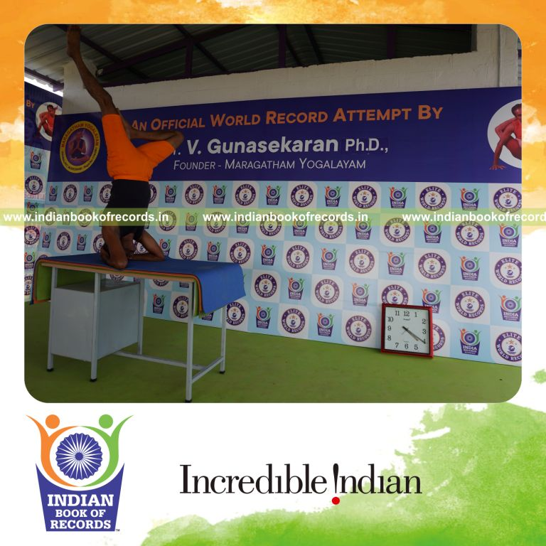 individual holding daksina ardha sirsasana yoga pose blindfolded on a table for record in Indian Book of Records