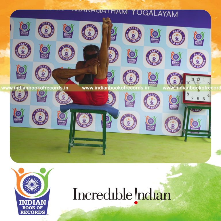 individual holding daksina ardha urdhva mukha paschimottanasana yoga pose blindfolded on a stool for record in Indian Book of Records