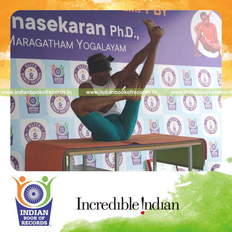 an individual holding daksina ardha urdhva mukha paschimottanasana yoga pose blindfolded on a table continuously for the longest duration with stability and control for a record in Indian Book of Records