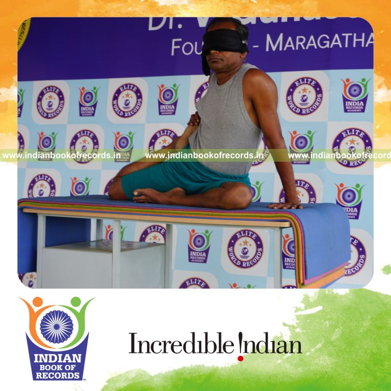individual holding daksina ardha vamadevasana yoga pose blindfolded on a table for record in Indian Book of Records