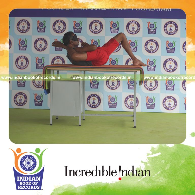 individual holding daksina bhairavasana yoga pose blindfolded on a table for record in Indian Book of Records