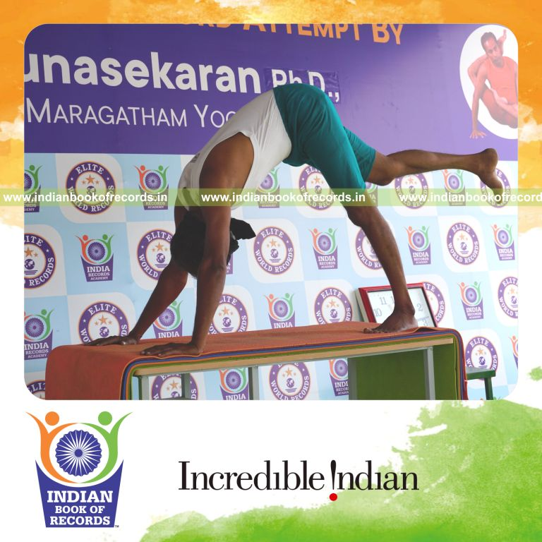 an individual holding daksina ekapada adho mukha svanasana yoga pose blindfolded on a table continuously for the longest duration with control and balance for a record in Indian Book of Records