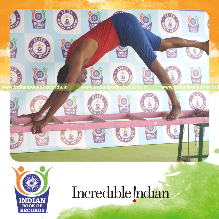 individual holding daksina ekapada adho mukha svanasana yoga pose on a ladder for record in Indian Book of Records