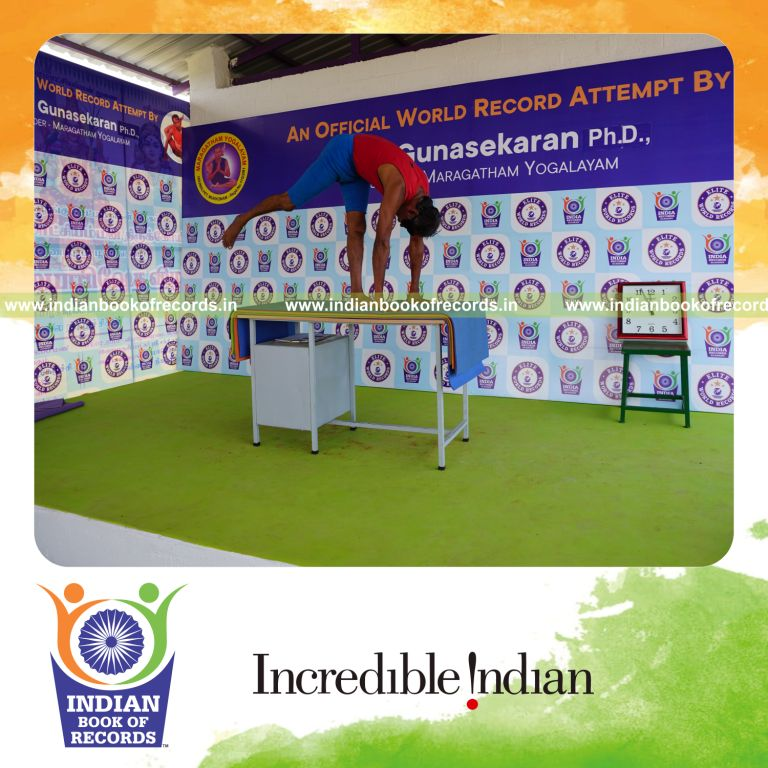individual holding daksina ekapada padahasthasana yoga pose blindfolded on a table for record in Indian Book of Records