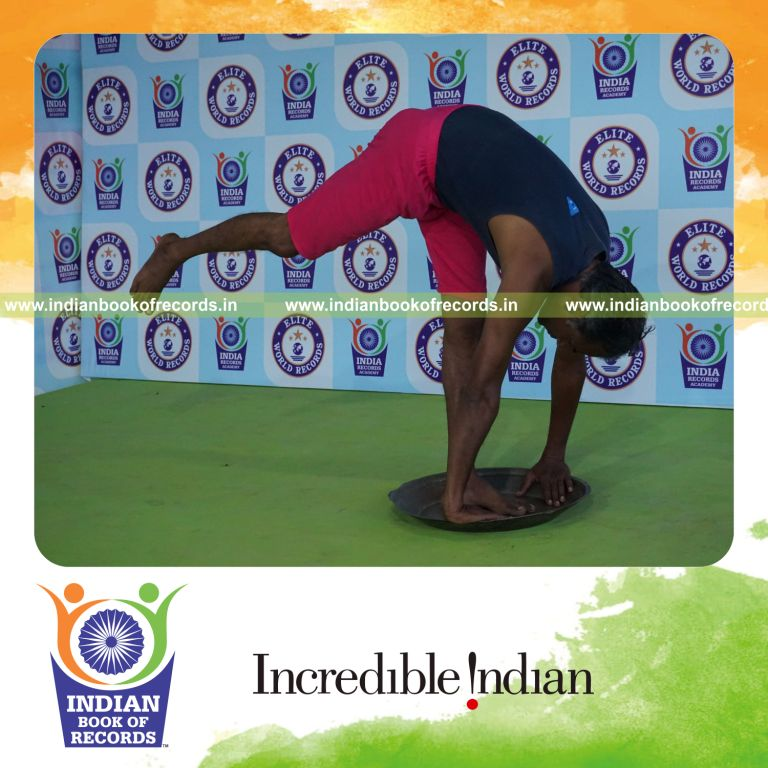 individual holding daksina ekapada padahasthasana yoga pose on a brass plate for record in Indian Book of Records