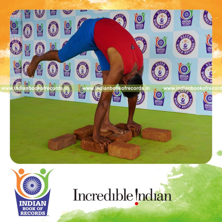 individual holding daksina ekapada padahasthasana yoga pose on bricks for record in Indian Book of Records