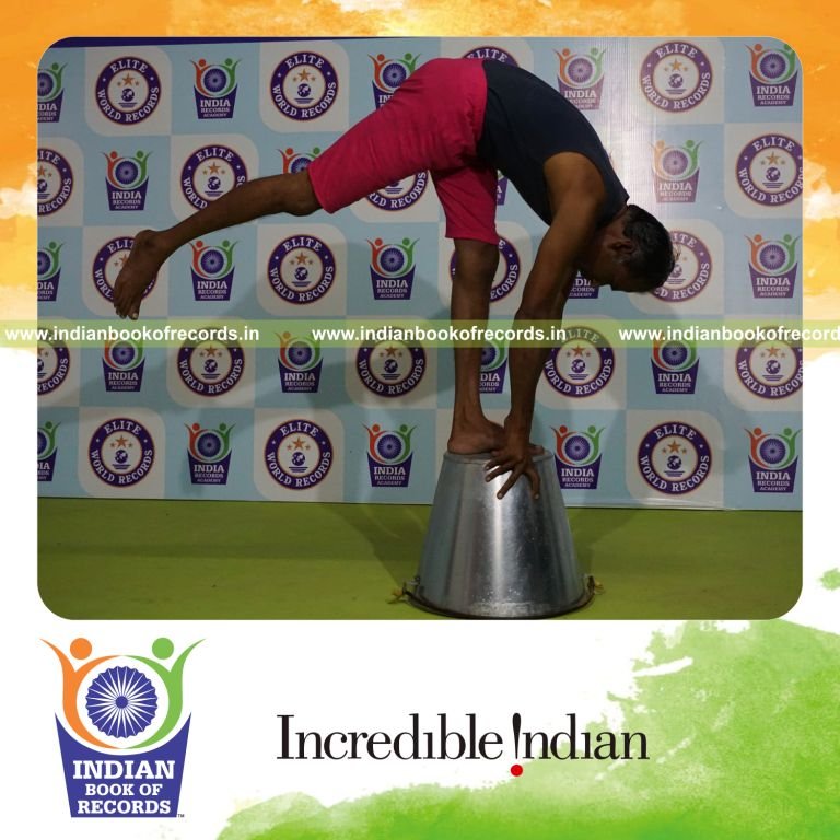 individual holding daksina ekapada padahasthasana yoga pose on a bucket for record in Indian Book of Records