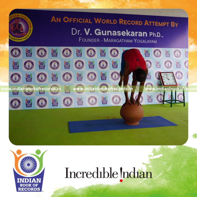 individual holding daksina ekapada padahasthasana yoga pose on a pot for record in Indian Book of Records