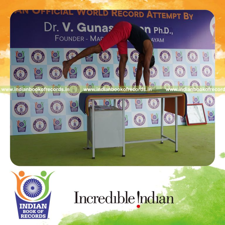 individual holding daksina ekapada padahasthasana yoga pose on a table for record in Indian Book of Records