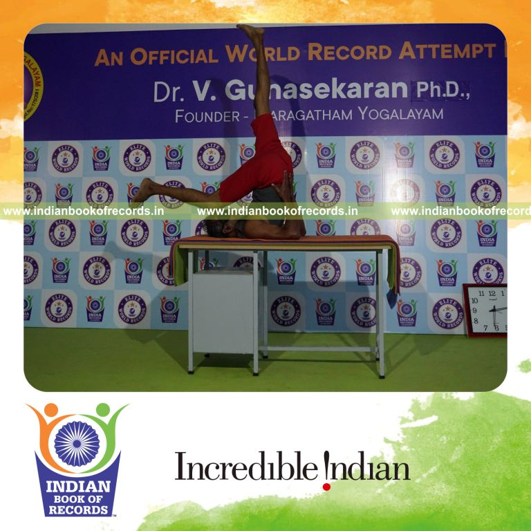 individual holding daksina ekapada sarvangasana yoga pose blindfolded on a table for record in Indian Book of Records
