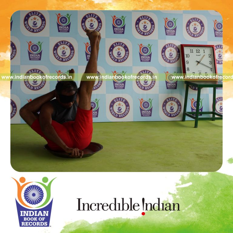 individual holding daksina ekapada sirasa krounchasana yoga pose blindfolded on a brass plate for record in Indian Book of Records