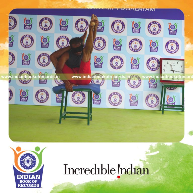 individual holding daksina ekapada sirasa krounchasana yoga pose blindfolded on a stool for record in Indian Book of Records