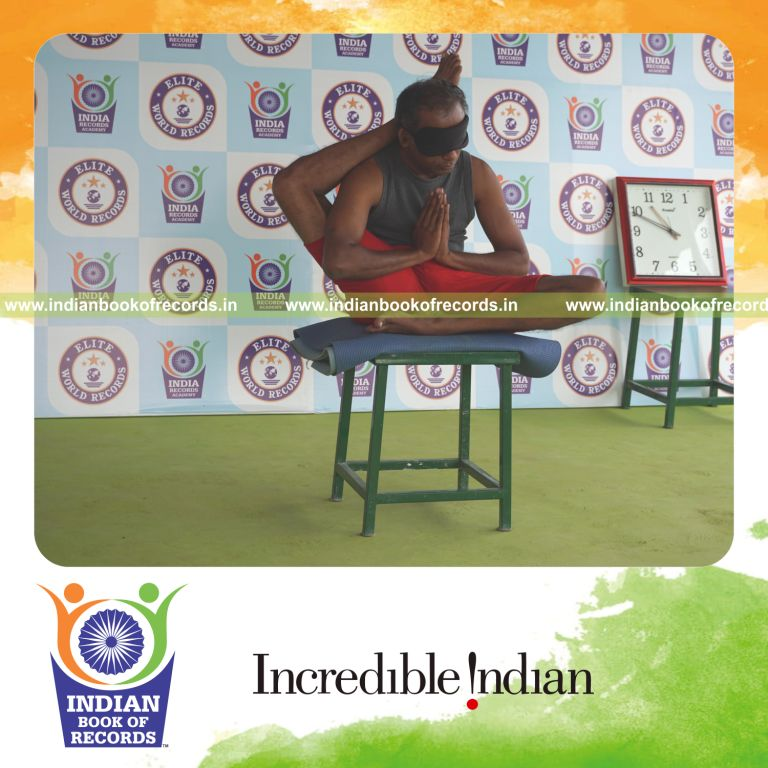 individual holding daksina ekapada sirsasana yoga pose blindfolded on a stool for record in Indian Book of Records