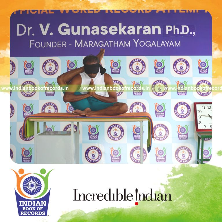 individual holding daksina ekapada sirsasana yoga pose blindfolded on a table for record in Indian Book of Records