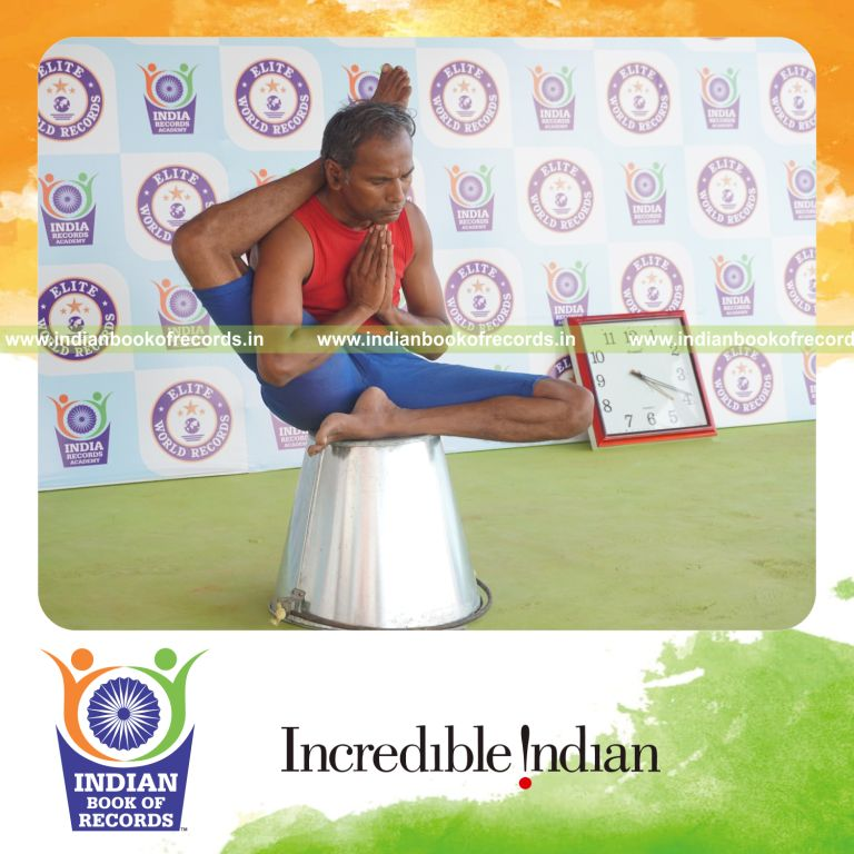 individual holding daksina ekapada sirsasana yoga pose on a bucket for record in Indian Book of Records
