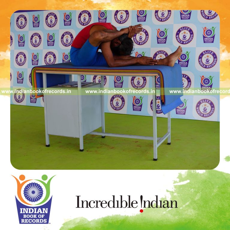 individual holding daksina ekapada skandasana yoga pose blindfolded on a table for record in Indian Book of Records