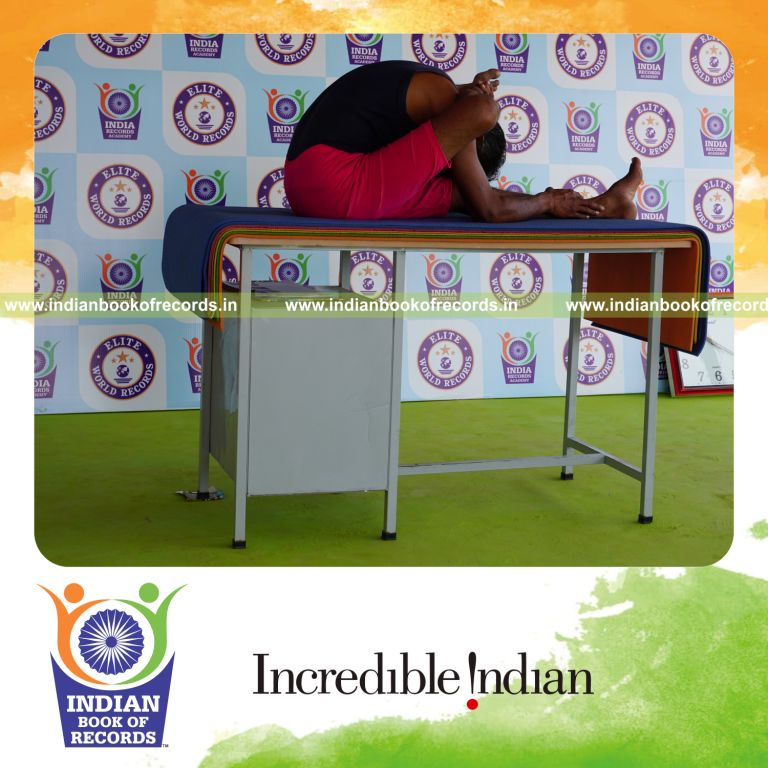 individual holding daksina ekapada skandasana yoga pose on a table for record in Indian Book of Records