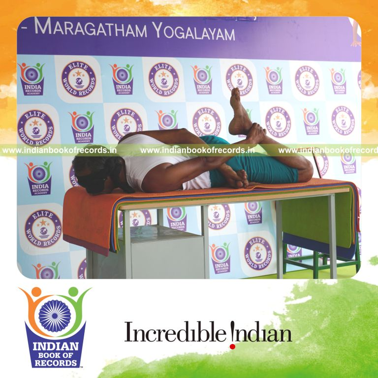 individual holding daksina gherandasana second type yoga pose blindfolded on a table for record in Indian Book of Records
