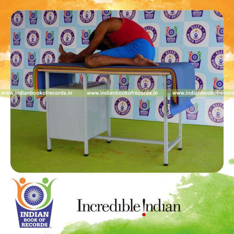 individual holding daksina gomukha janu sirsasana yoga pose blindfolded on a table for record in Indian Book of Records