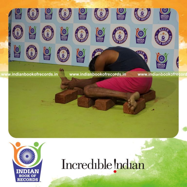 individual holding daksina gomukha janu sirsasana yoga pose on bricks for record in Indian Book of Records
