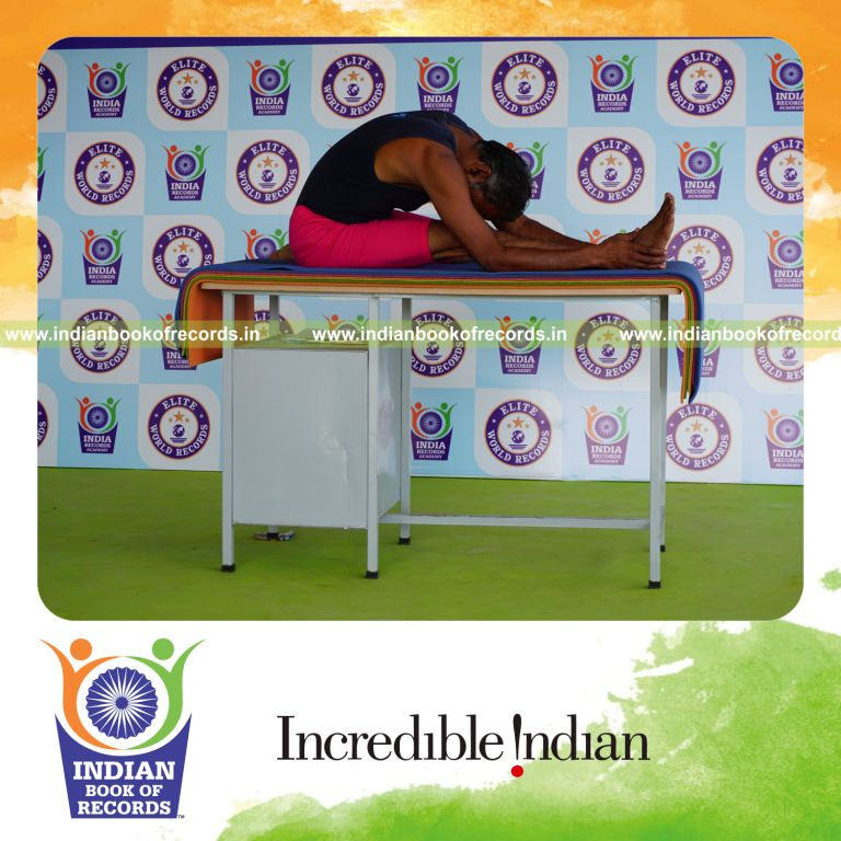 individual holding daksina gomukha janu sirsasana yoga pose on a table for record in Indian Book of Records