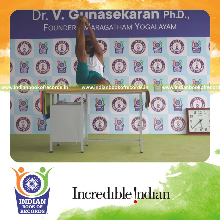 individual holding daksina gomukha krounchasana yoga pose blindfolded on a table for record in Indian Book of Records
