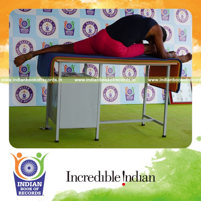 individual holding daksina hanumana paschimottanasana yoga pose on a table for record in Indian Book of Records