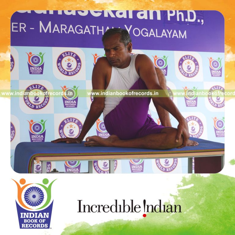 individual holding daksina janu ardha matsyendrasana yoga pose on a table for record in Indian Book of Records