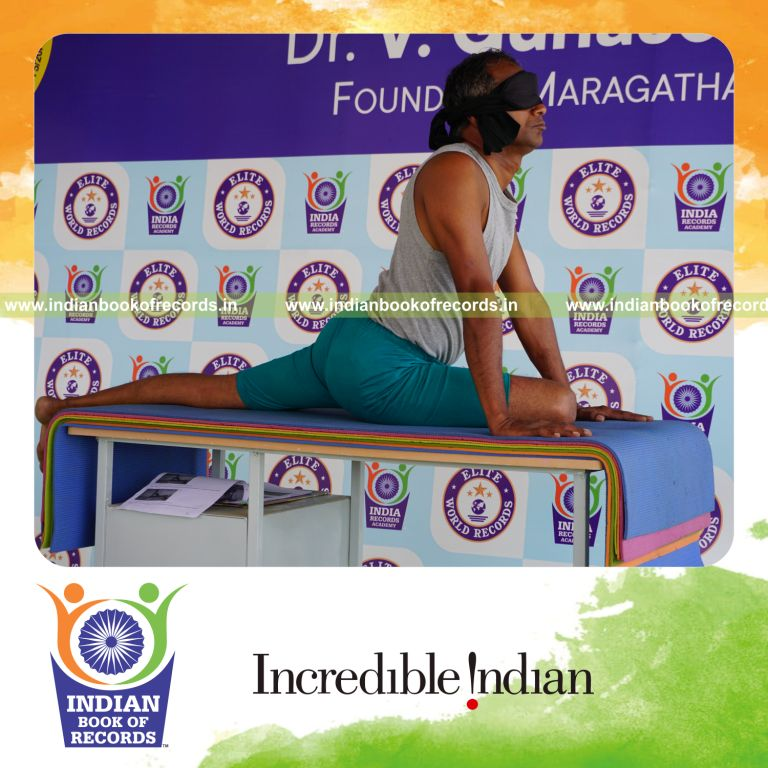 individual holding daksina janu bhujangasana yoga pose blindfolded on a table for record in Indian Book of Records
