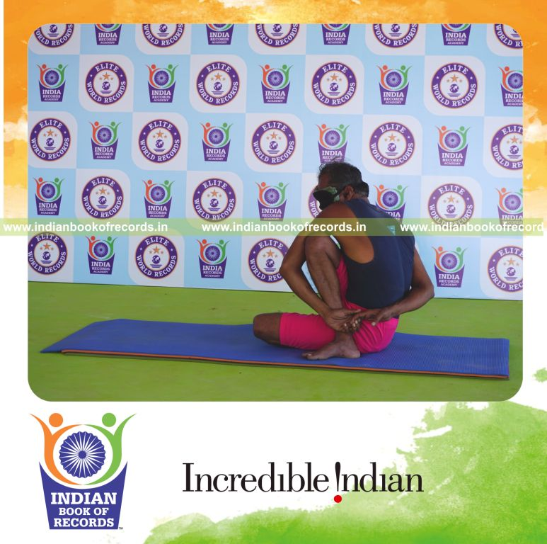 an individual holding daksina janu parivrtta ardha matsyendrasana yoga pose blindfolded for the longest duration with flexibility and control for a record in Indian Book of Records