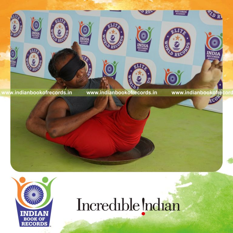 individual holding daksina kala bhairavasana yoga pose blindfolded on a brass plate for record in Indian Book of Records