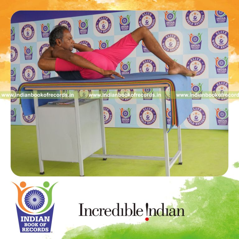 individual holding daksina kala bhairavasana yoga pose on a table for record in Indian Book of Records
