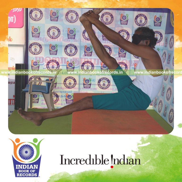 an individual holding daksina krounchasana yoga pose blindfolded on a table continuously for the longest duration with control and balance for a record in Indian Book of Records