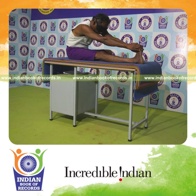 individual holding daksina mahamudra yoga pose blindfolded on a table for record in Indian Book of Records