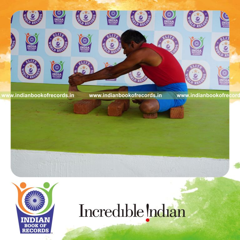individual holding daksina mahamudra yoga pose on bricks for record in Indian Book of Records